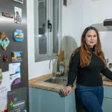 Mujer en cocina, con imanes de viajes en la nevera. Una opción para tu futuro hogar: alquiler con opción a compra entre particulares.