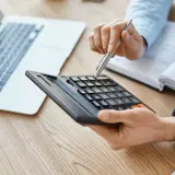 Persona calculando con calculadora y portátil, quizás para entender qué es el IBI.
