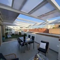 Cerramiento terraza casa unifamiliar con mesa y sillas, y zona ajardinada. Disfruta del exterior todo el año.