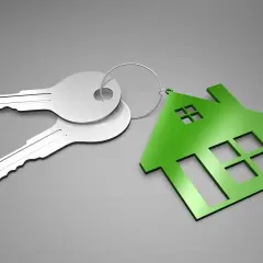 Dos llaves plateadas y un llavero con forma de casa verde. ¿Qué es el aval ico? Es la llave de tu nuevo hogar.
