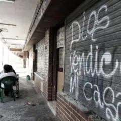 Gente sentada en sillas de plástico frente a un local con grafitis, reflejo de los peores barrios de Madrid.