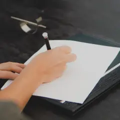 Mano escribiendo en un documento. Cualquier persona interesada en saber quién puede pedir una nota simple, puede hacerlo para verificar información.