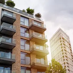 Edificio moderno con balcones de cristal y ladrillo, parte de una parcela construida sin división horizontal.