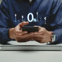 Man using smartphone with 0% interest and currency symbols, ideal for managing comisiones bancarias comunidades de propietarios.