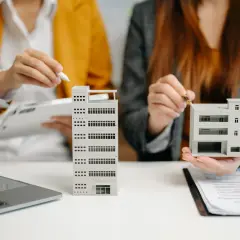 Dos personas analizan maquetas de edificios, como si estuvieran evaluando qué es un informe pericial inmobiliario.