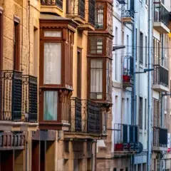 Edificios antiguos con balcones de hierro forjado y ventanales que evocan un caudal hereditario de historia y arquitectura.