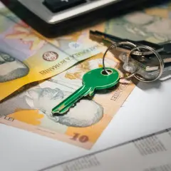 Llaves verdes y dinero rumano sobre documentos, sugiriendo un contrato de arras entre particulares para una compra.