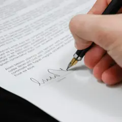 Firma de un certificado de deuda cero. La mano escribe con una pluma estilográfica sobre un documento legal.