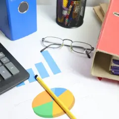 Calculadora, gráficos y carpetas sobre un escritorio. Analizando el tipo de interés actual para tomar decisiones financieras.
