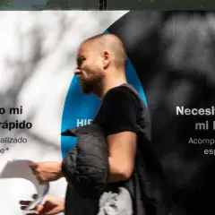 Hombre pasa frente a un anuncio que dice "Necesito mi hipoteca rápido" y "Necesito entender mi hipoteca". Pregunta: ¿quién paga el levantamiento de hipoteca?
