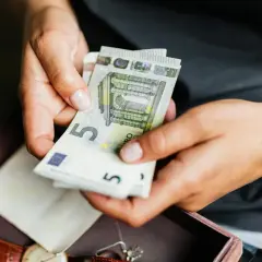 Manos contando billetes de 5 euros. No pagues la comunidad o te pueden quitar la casa.
