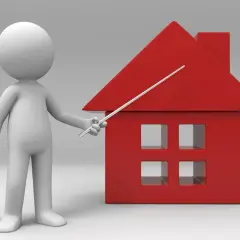 Un muñeco blanco señala una casa roja. Un piso es un inmueble, y esta casa representa uno.