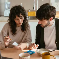 Pareja revisando facturas y usando calculadora, gestionando su comunidad de bienes entre familiares.