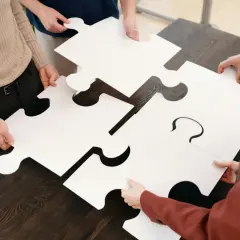 Manos unen piezas de rompecabezas gigantes, simbolizando la complejidad de una simulación de hipoteca.