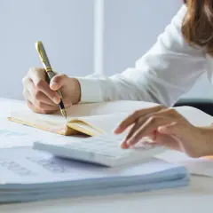 Persona revisa documentos y usa calculadora. Se prepara para declarar la nuda propiedad en la renta.