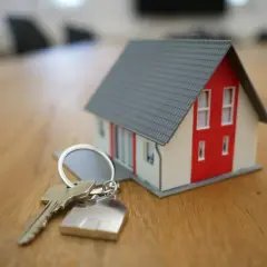 Llaves de una casa modelo sobre una mesa de madera, simbolizando la nueva ley de vivienda y la esperanza de un hogar.