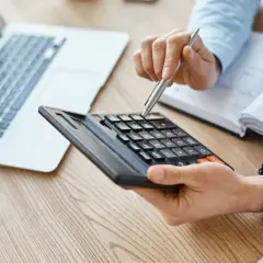 Persona calculando con calculadora y portátil, quizás para entender qué es el IBI.