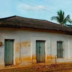 Casa antigua con tejas oscuras, dos puertas verdes y una ventana enrejada. El **precio** de esta **declaración de obra nueva antigua** es negociable.