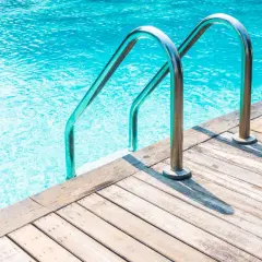 Escaleras de piscina de acero inoxidable sobre cubierta de madera. ¿Cuánto cuesta hacer una piscina?