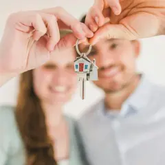 Pareja feliz sosteniendo llaves de casa. ¿Cuánto cobra Tecnocasa por vender un piso?
