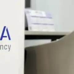 Logo de "LA CASA agency" en un cartel blanco, con sillas de oficina al fondo. Buscando la casa agency opiniones.