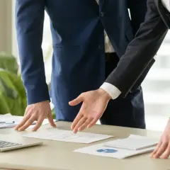 Dos hombres de negocios analizan un plano. Se discute el precio del informe pericial arquitecto.