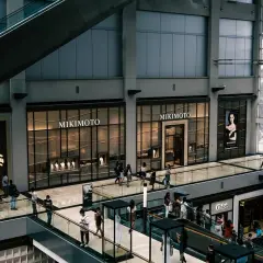 Interior de centro comercial con escaleras mecánicas y tiendas de lujo. La tasación de locales comerciales es clave para el valor de estos espacios.