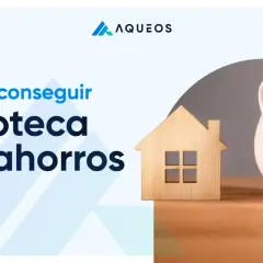 Cómo conseguir hipoteca sin ahorros. Una casa de madera y una hucha rota con monedas simbolizan el sueño de la vivienda.