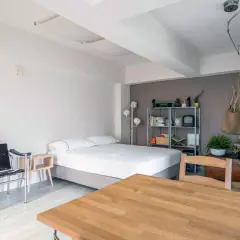 Acogedor espacio en apartamentos o estudios con cama, silla de diseño y mesa de madera.