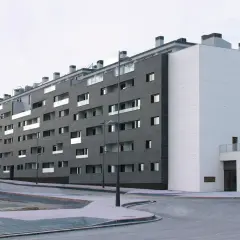 Edificio moderno con fachada de piedra oscura y blanca. ¿Buscas como saber si una vivienda es VPO? Este edificio podría serlo.