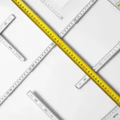 Reglas de medición de diferentes tipos, incluyendo una cinta métrica amarilla, dispuestas en un patrón que sugiere la búsqueda de un cuerpo cierto.