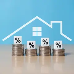 Montones de monedas con cubos de porcentaje y un contorno de casa. ¿Cuánto hay que tener ahorrado para comprar un piso?