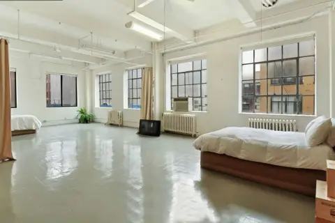 Espacio diáfano con camas y cortinas, ideal para un cambio de uso de vivienda a local.