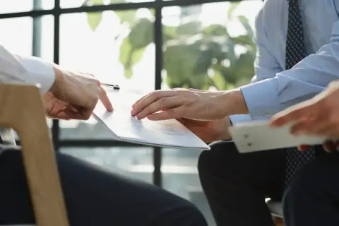 Manos revisando un documento, discutiendo cómo pedir nota simple.