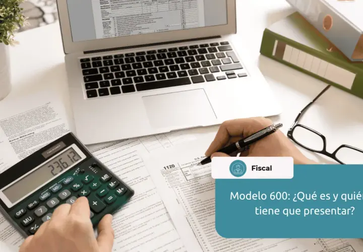 Calculadora, gafas, portátil y documentos fiscales sobre un escritorio.
