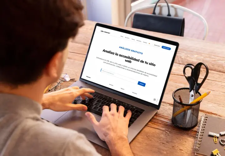 Persona usando laptop para obtener un informe de accesibilidad web. La pantalla muestra "Analiza la accesibilidad de tu sitio web".