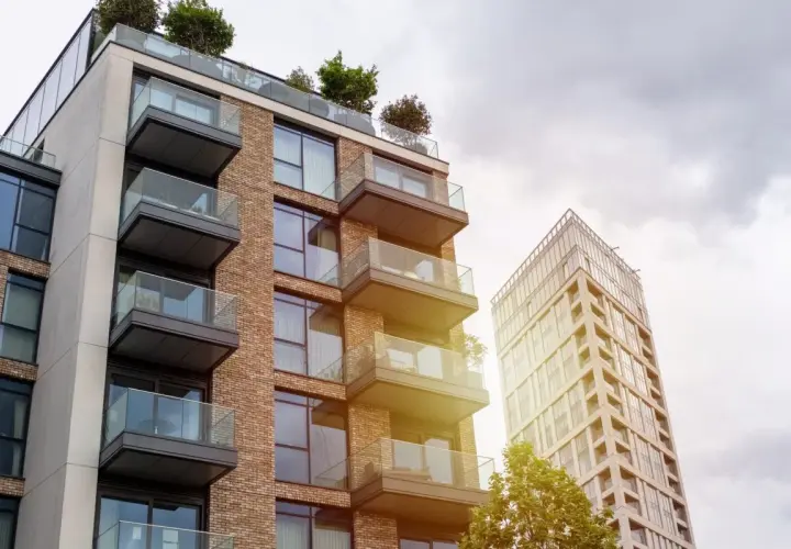 Edificio moderno con balcones de cristal y ladrillo, parte de una parcela construida sin división horizontal.