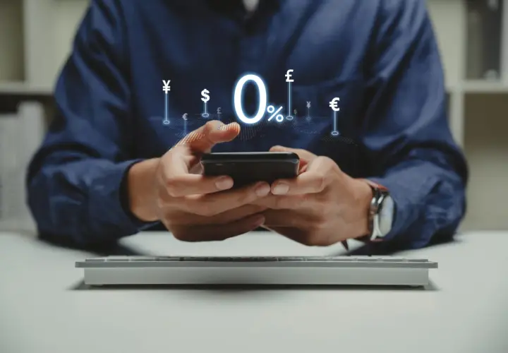 Man using smartphone with 0% interest and currency symbols, ideal for managing comisiones bancarias comunidades de propietarios.