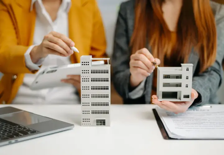 Dos personas analizan maquetas de edificios, como si estuvieran evaluando qué es un informe pericial inmobiliario.