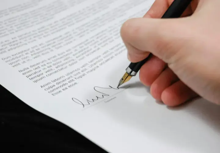 Firma de un certificado de deuda cero. La mano escribe con una pluma estilográfica sobre un documento legal.