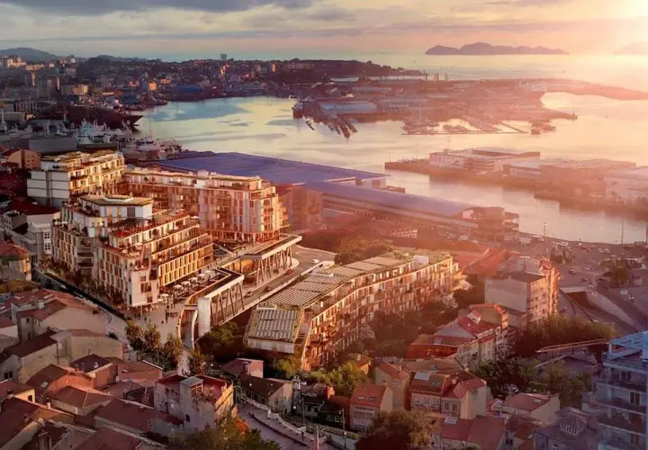 Vista aérea de un moderno complejo de edificios junto a un puerto, con islas al fondo. Un ejemplo de las mejores ciudades para vivir en España.