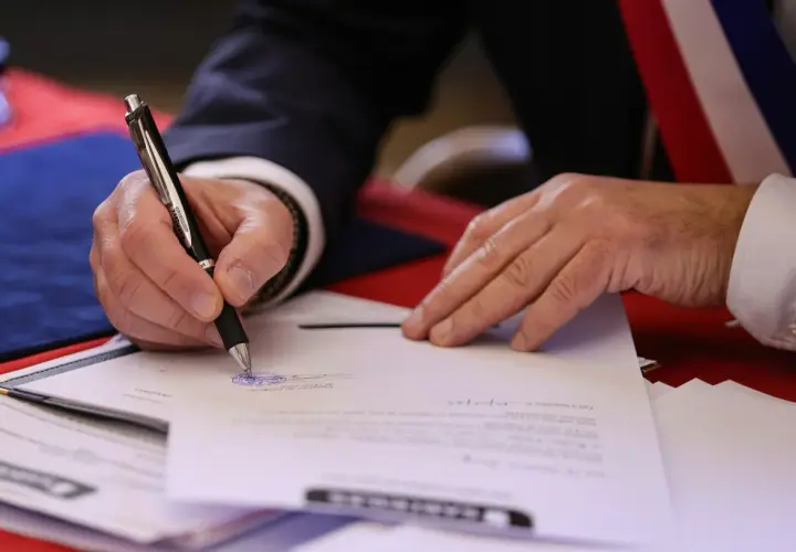 Mano firmando un documento oficial. El **valor pericial** de este acto es la validación de un acuerdo o testimonio.
