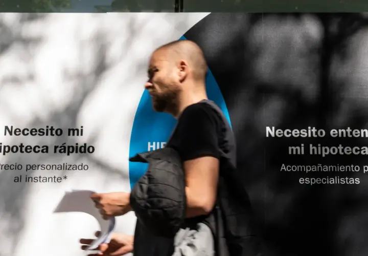Hombre pasa frente a un anuncio que dice "Necesito mi hipoteca rápido" y "Necesito entender mi hipoteca". Pregunta: ¿quién paga el levantamiento de hipoteca?