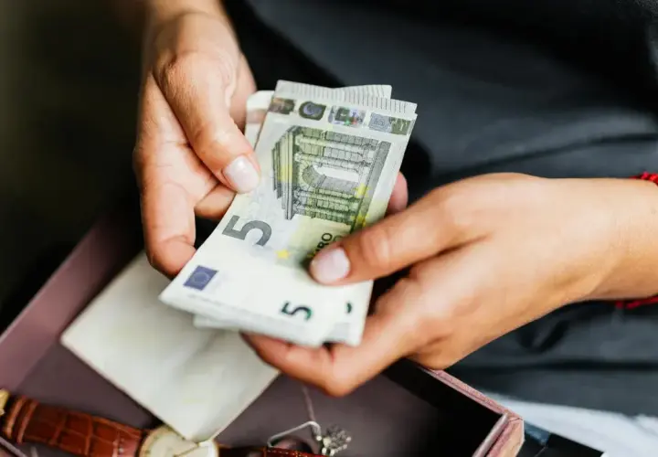 Manos contando billetes de 5 euros. No pagues la comunidad o te pueden quitar la casa.