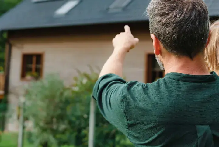 Padre e hija contemplan su futuro hogar. El padre señala el terreno, soñando con las hipotecas autopromotor que harán realidad su casa ideal.