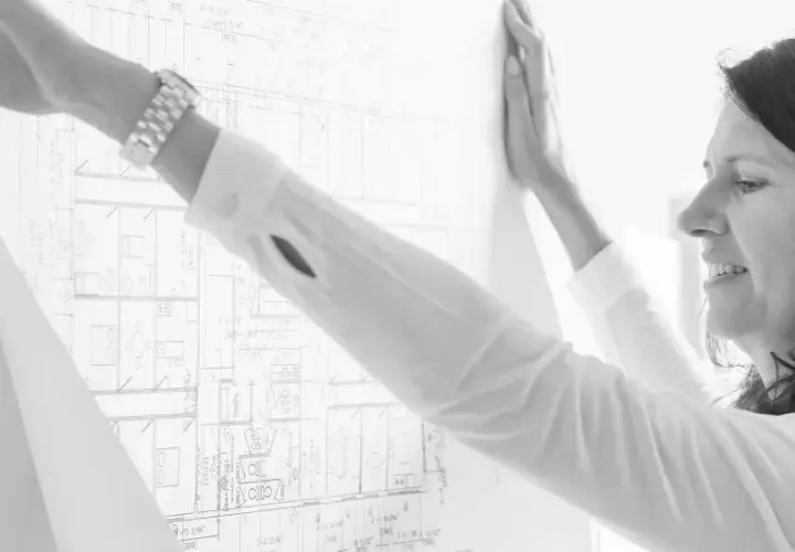Mujer revisa un plano detallado, parte de un levantamiento de planos para un proyecto arquitectónico.