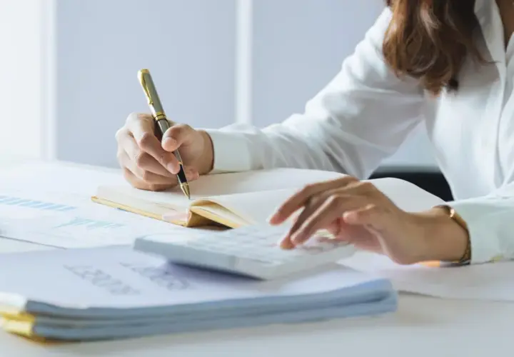Persona revisa documentos y usa calculadora. Se prepara para declarar la nuda propiedad en la renta.