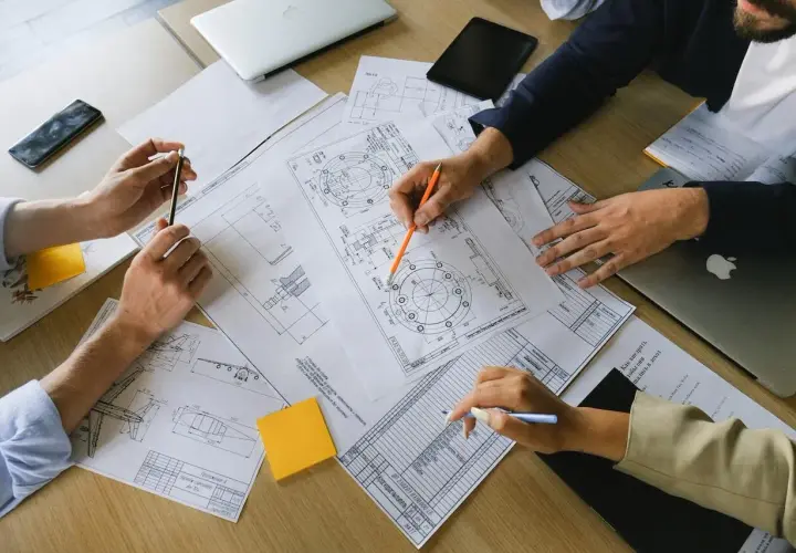 Manos revisando planos técnicos, un **informe pericial vivienda** en proceso.