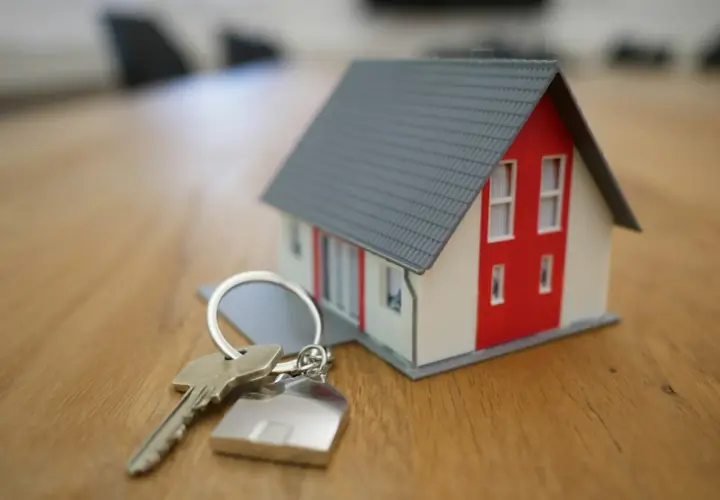 Llaves de una casa modelo sobre una mesa de madera, simbolizando la nueva ley de vivienda y la esperanza de un hogar.
