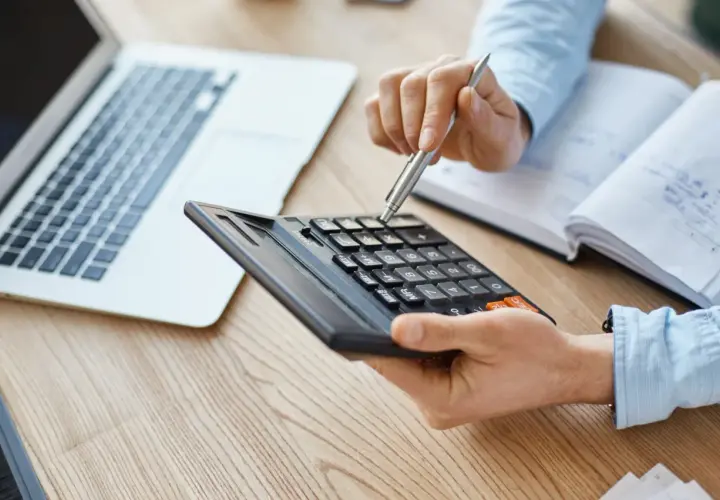 Persona calculando con calculadora y portátil, quizás para entender qué es el IBI.